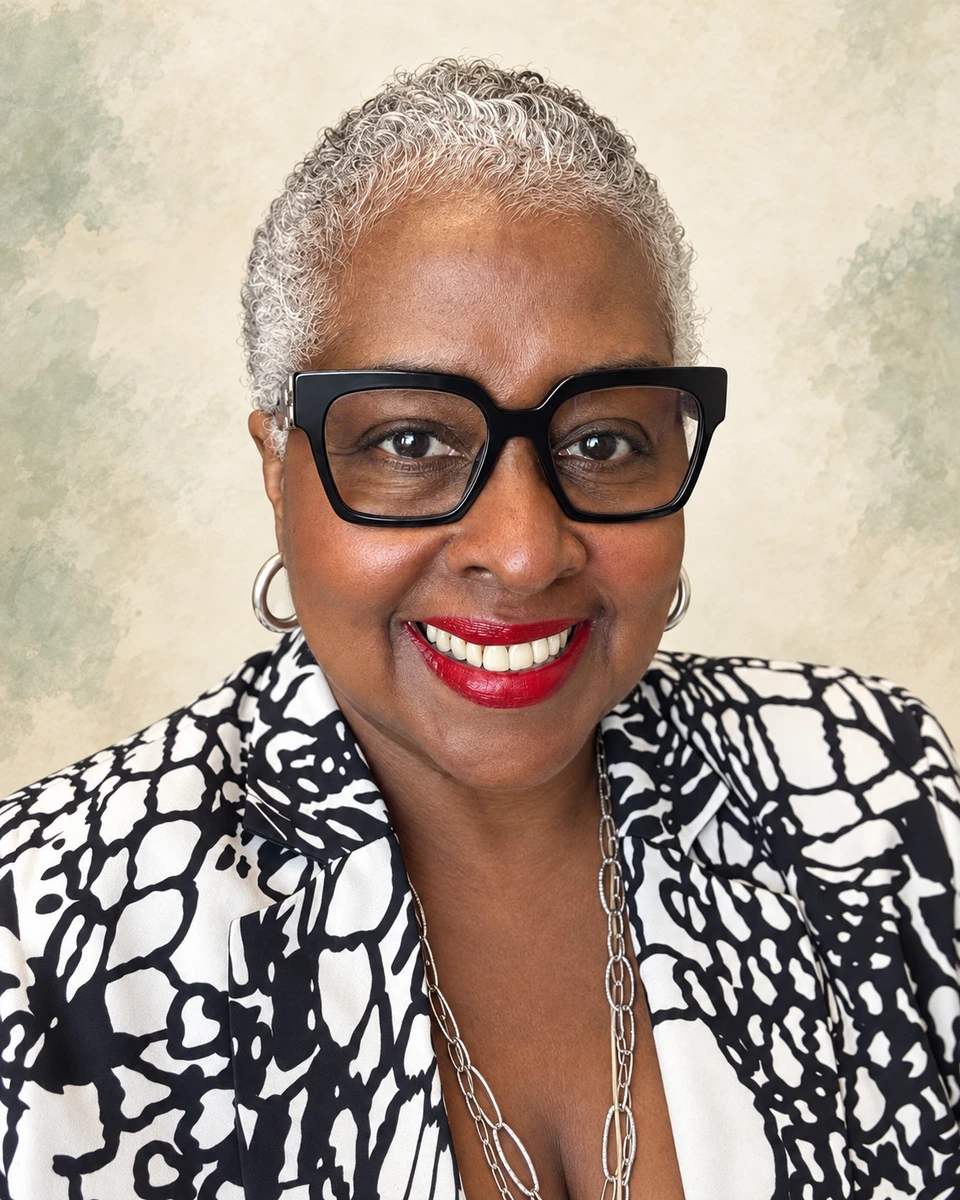 Sharon Saunders smiling, wearing black glasses and a patterned blouse.